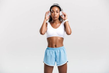 Müzik dinleyen kendinden emin, fit, Afrikalı bir sporcu kadın.