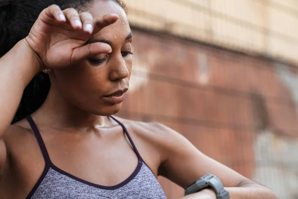 Bild einer müden afrikanisch-amerikanischen Frau, die auf eine Armbanduhr blickt — Stockfoto