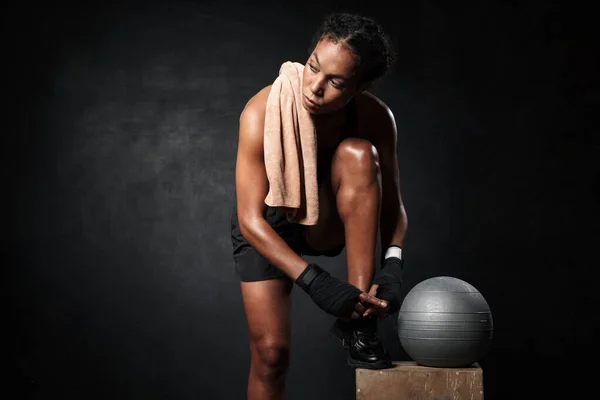 Obrázek africké americké ženy vázání její tenisky tkaničky fitness míč — Stock fotografie