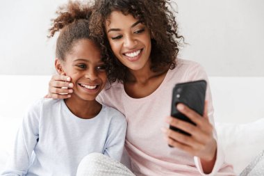 Amerikalı bir kadın ve küçük kızının cep telefonu kullanırken görüntüsü. 