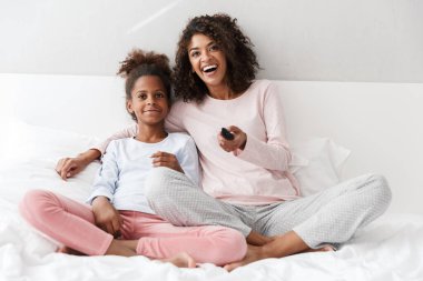 Afro-Amerikan kadın ve kızının TV izlediği görüntü 