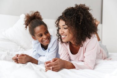 Gülümseyen genç anne ve küçük kızı pijama giyiyordu.