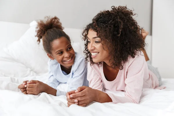 Lächelnde junge Mutter und ihre kleine Tochter im Schlafanzug — Stockfoto