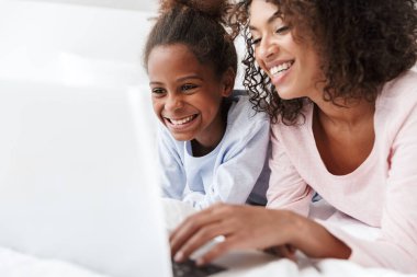 Gülümseyen genç anne ve küçük kızı pijama giyiyordu.