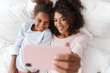 Gülümseyen genç anne ve küçük kızı pijama giyiyordu.