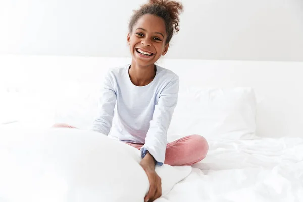 Εικόνα του Αφροαμερικανού κοριτσιού που χαμογελά και κάθεται στο κρεβάτι — Φωτογραφία Αρχείου