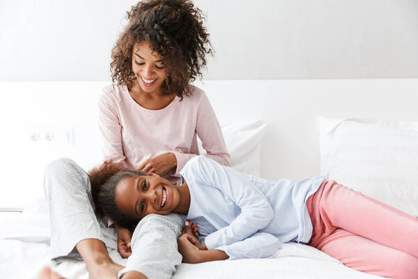 Image of cheerful african american woman and her little daughter