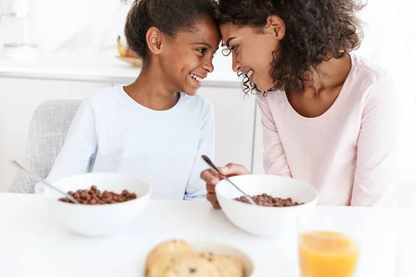 Image of american woman and her daughter having breakfast in kit