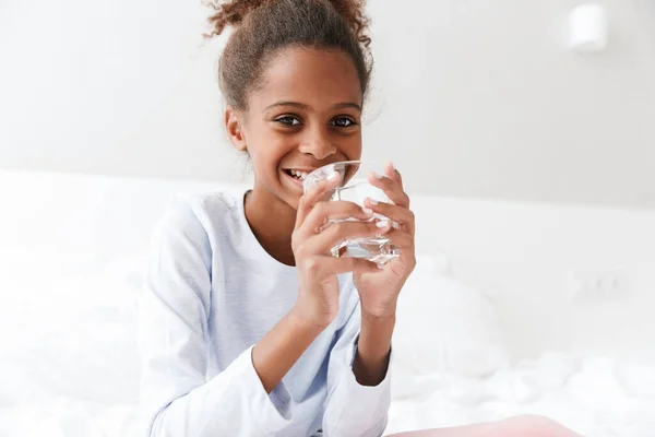 Зображення щасливої афроамериканської маленької дівчинки, що п'є воду в — стокове фото