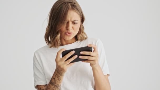 Opgewonden Jonge Vrouw Draagt Basic Shirt Enthousiast Spelen Haar Smartphone — Stockvideo