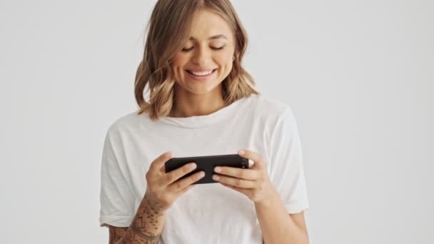 Sorrindo Jovem Mulher Vestindo Camiseta Básica Usando Seu Smartphone Horizontalmente — Vídeo de Stock