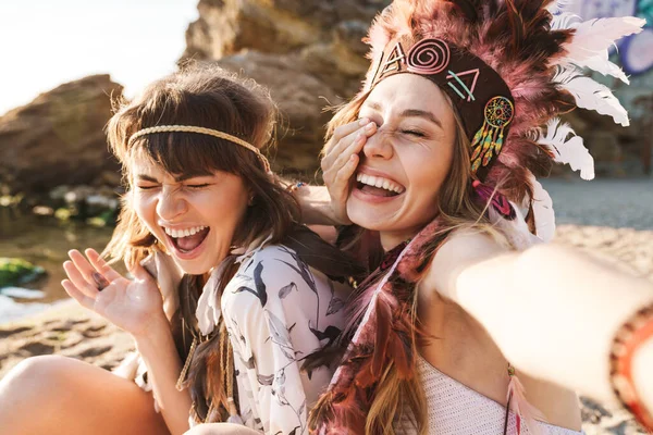 Изображение прекрасных хиппи-девушек, смеющихся и делающих селфи по морю — стоковое фото