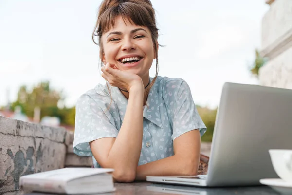 Emotional happy young beautiful woman using laptop computer on a balcony. — Stock Photo, Image