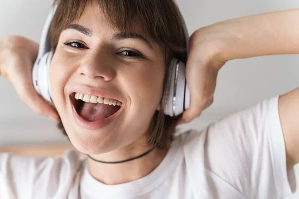 Glücklich fröhlich erstaunlich junge Dame drinnen zu Hause Musik hören mit Kopfhörern. — Stockfoto