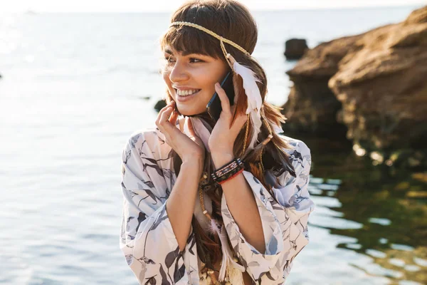 Imagen de chica hippy en diadema de plumas hablando en el teléfono celular por — Foto de Stock