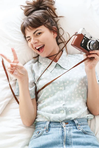 Heureuse femme positive gaie à l'intérieur à la maison se trouve sur le lit le matin tenant caméra . — Photo