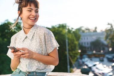 Mutlu, neşeli, genç bir kadın balkonda cep telefonu sohbeti yapıyor..