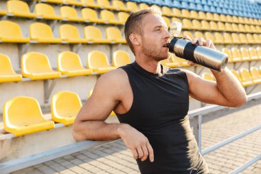Genç sporcunun boş stadyum koltuklarında su içişi.