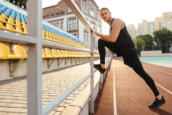 Hombre de deportes hacer ejercicios de estiramiento en el estadio . — Foto de Stock