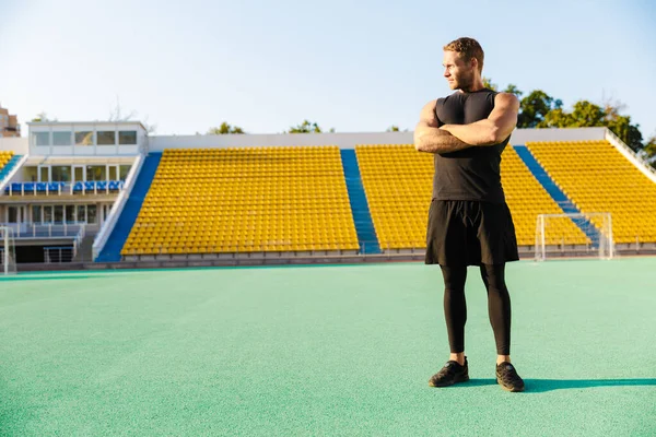 Imagen del hombre atlético parado en el campo de deportes mientras hace trabajo — Foto de Stock