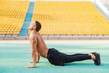 Spor salonunda vücudunu esneten atletik bir adamın görüntüsü.