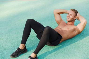 Yeşil spor sahasında yatan ve çapraz çizim yapan bir adam. 