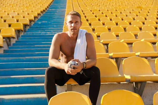 Obrázek bělocha bez košile sportovec pitné vody na stadionu — Stock fotografie