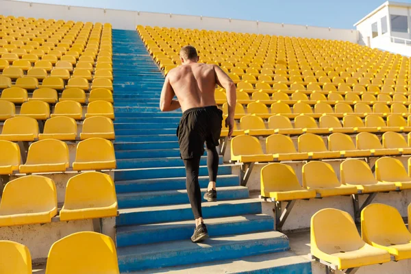 Imagen del deportista corriendo por asientos vacíos del estadio mientras hace wo — Foto de Stock