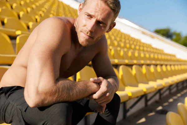Obrázek sportovce bez trička sedícího během práce na sedadle stadionu — Stock fotografie