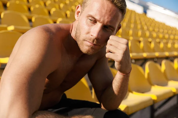 Obrázek sportovce bez trička sedícího během práce na sedadle stadionu — Stock fotografie