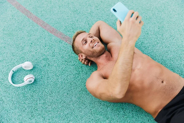 Εικόνα του ανθρώπου που κρατά smartphone, ενώ βρίσκεται στο green sports grou — Φωτογραφία Αρχείου
