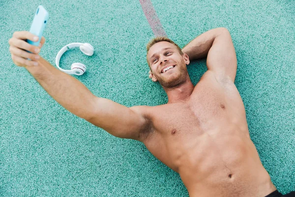 Image of shirtless man taking selfie at smartphone on green spor — Stock Photo, Image