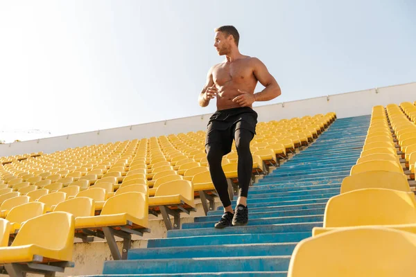 Imagem de um desportista sem camisa saudável a correr pelo estádio vazio se — Fotografia de Stock