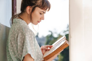 Balkonda kitap okuyan çok tatlı bir genç kadın..