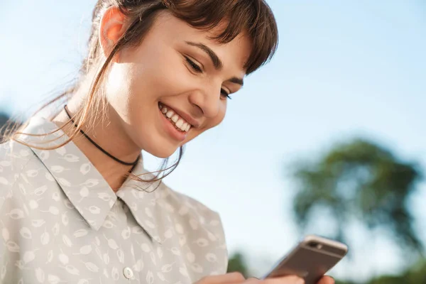 Positive cheery happy young beautiful woman on a balcony using mobile phone chatting. — Stock Photo, Image