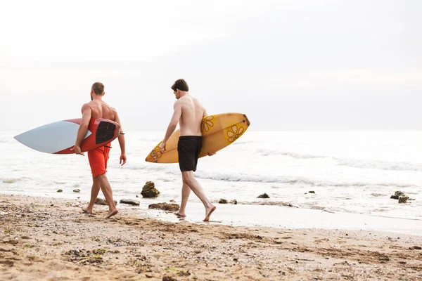 Två män surfar vänner på en strand utanför. — Stockfoto