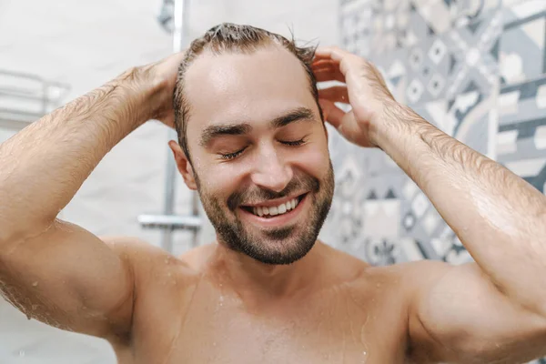 Ελκυστικός νέος χαμογελαστός άντρας που πλένει μαλλιά — Φωτογραφία Αρχείου