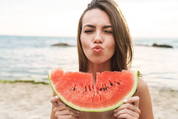 Beeld van aantrekkelijke gelukkige vrouw eten watermeloen en het maken van kus lippen — Stockfoto