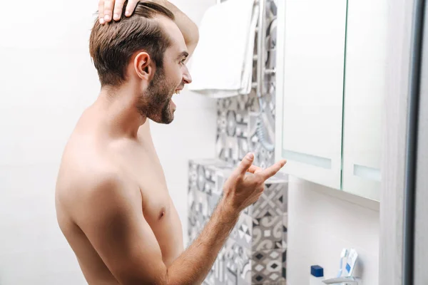 Šťastný mladý muž bez trička, dívající se na sebe na záchodě — Stock fotografie