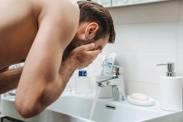 Handsome young shirtless man washing his face — Stock Photo, Image