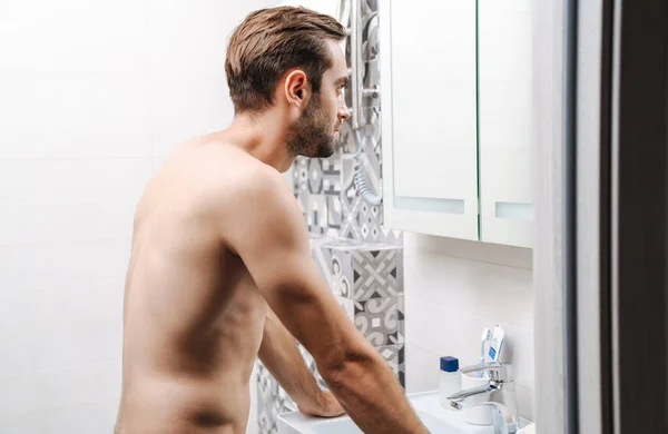 Heureux jeune homme torse nu qui se regarde dans la salle de bain — Photo