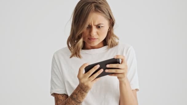 Serieus Vrouw Dragen Basic Shirt Spelen Haar Smartphone Geïsoleerd Witte — Stockvideo