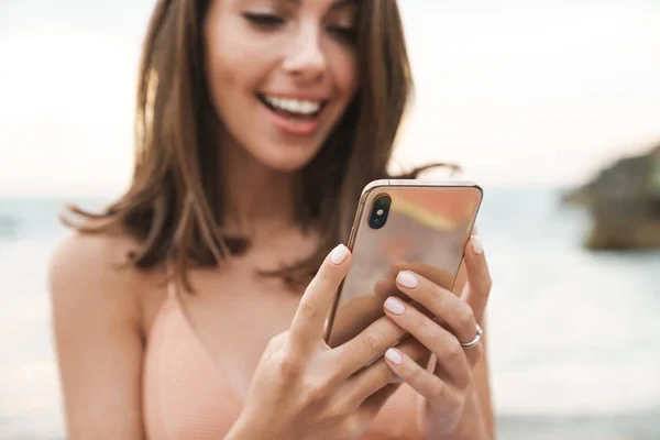 Beeld van mooie vrolijke vrouw glimlachend en met behulp van mobiele telefoon — Stockfoto