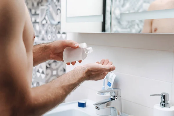 Handsome young shirtless man applying aftershave — Stock Photo, Image