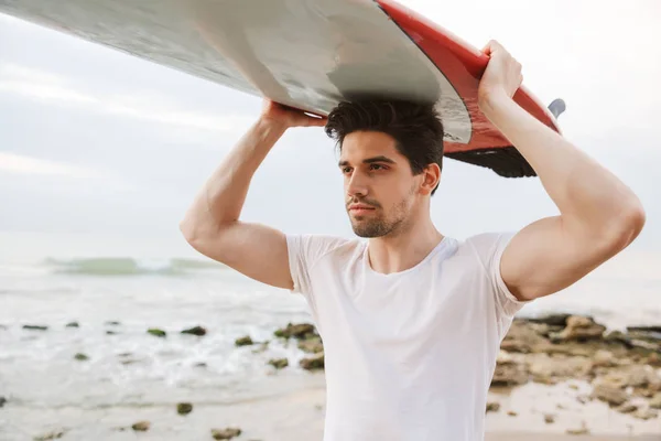 ハンサムな男サーファーでサーフィンでビーチの外. — ストック写真