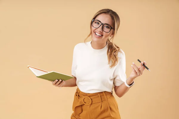 Bild einer fröhlichen Frau, die lächelt und Notizen in Tagebuch schreibt — Stockfoto