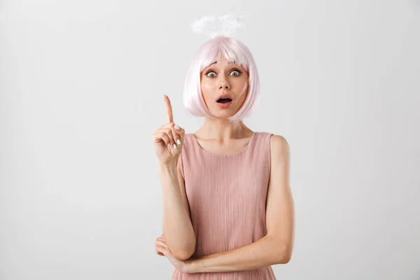Portrait of shocked nice woman wearing pink wig and toy halo looking at camera while pointing finger upward at copyspace — Stock Photo, Image