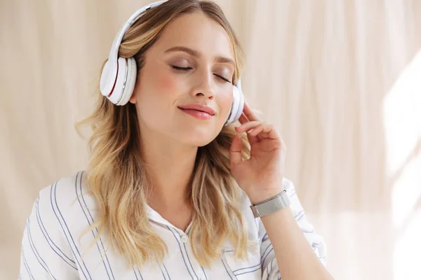 Imagen de una mujer rubia elegante y complacida escuchando música en la cabeza —  Fotos de Stock