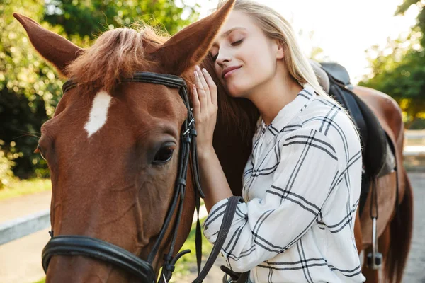 Εικόνα της χαρούμενης γυναίκας χαμογελά και στέκεται δίπλα στο άλογο στην αυλή σε γ — Φωτογραφία Αρχείου