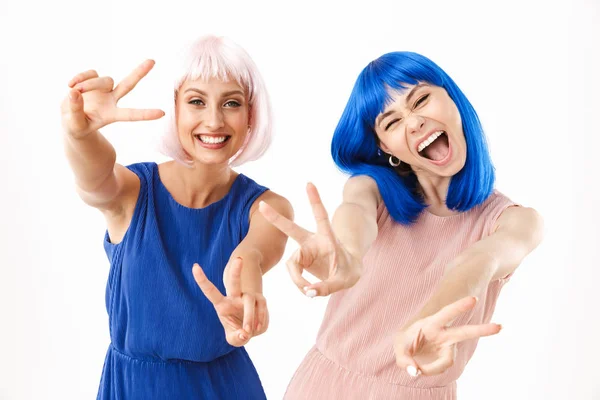 Portrét dvou vzrušených žen v modrých a růžových parukách s úsměvem při gestikulování znamení míru — Stock fotografie